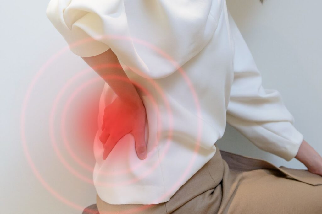 腰が痛み、腰に手を当てている人