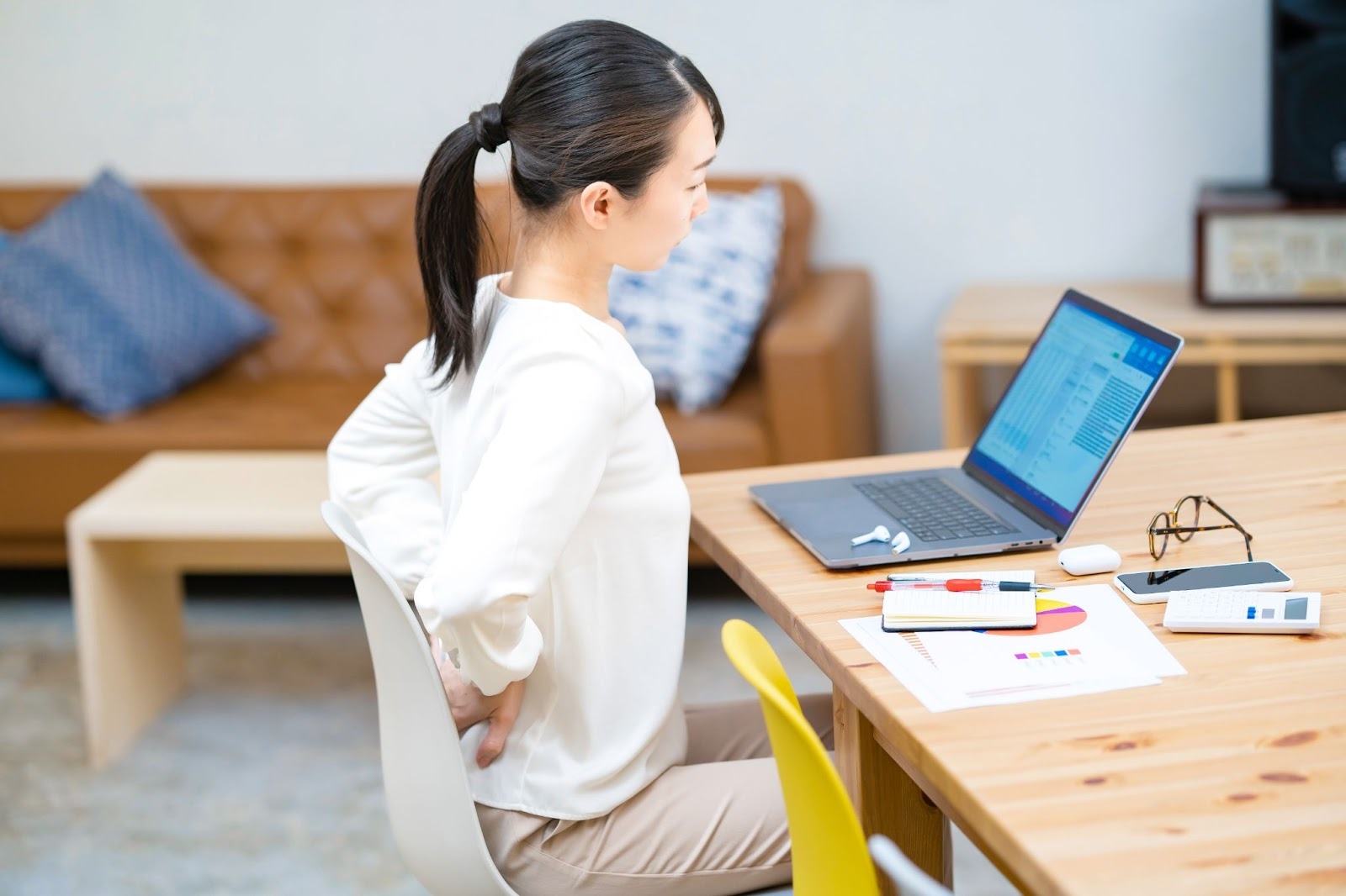 腰痛でつらそうなデスクワーク中の女性
