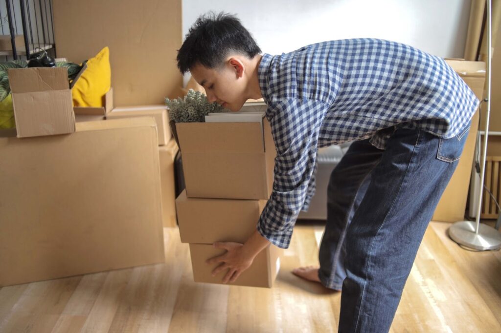 腰を曲げて床のものを持ち上げている男性