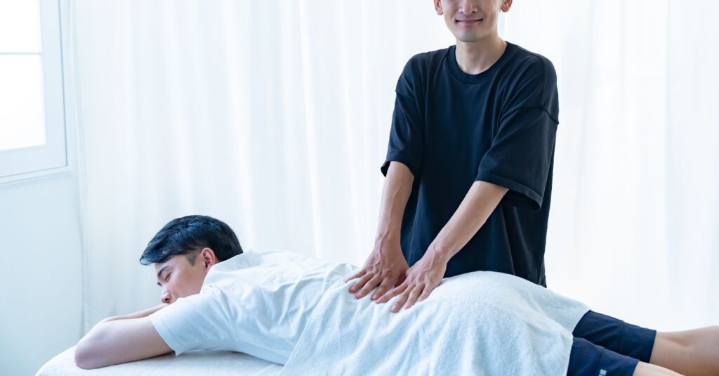 接骨院で柔道整復師による施術を受けるぎっくり腰の男性