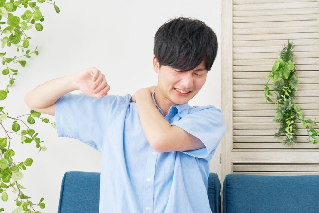 肩こりが痛くてつらそうな男性