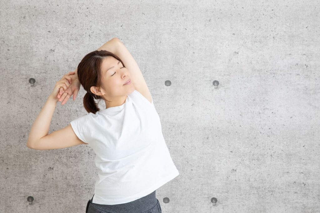 肩こりを悪化させないために肩のストレッチをしている女性