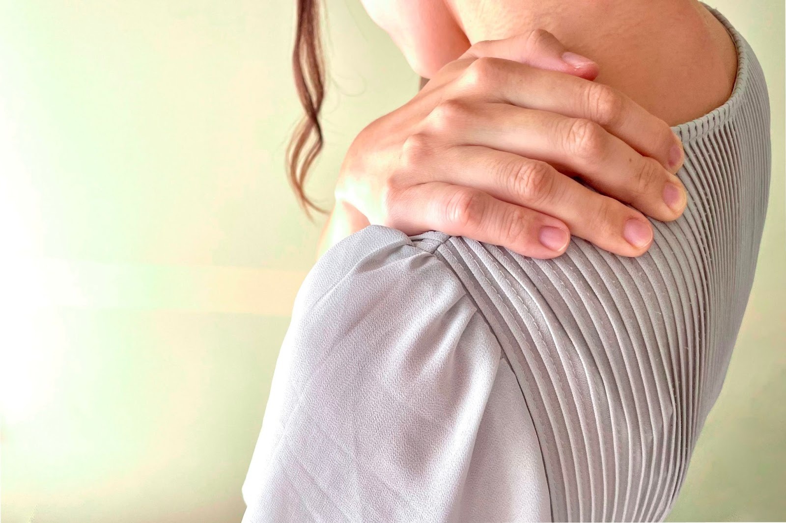 ひどすぎる肩こりがつらく、肩を手で押さえている女性