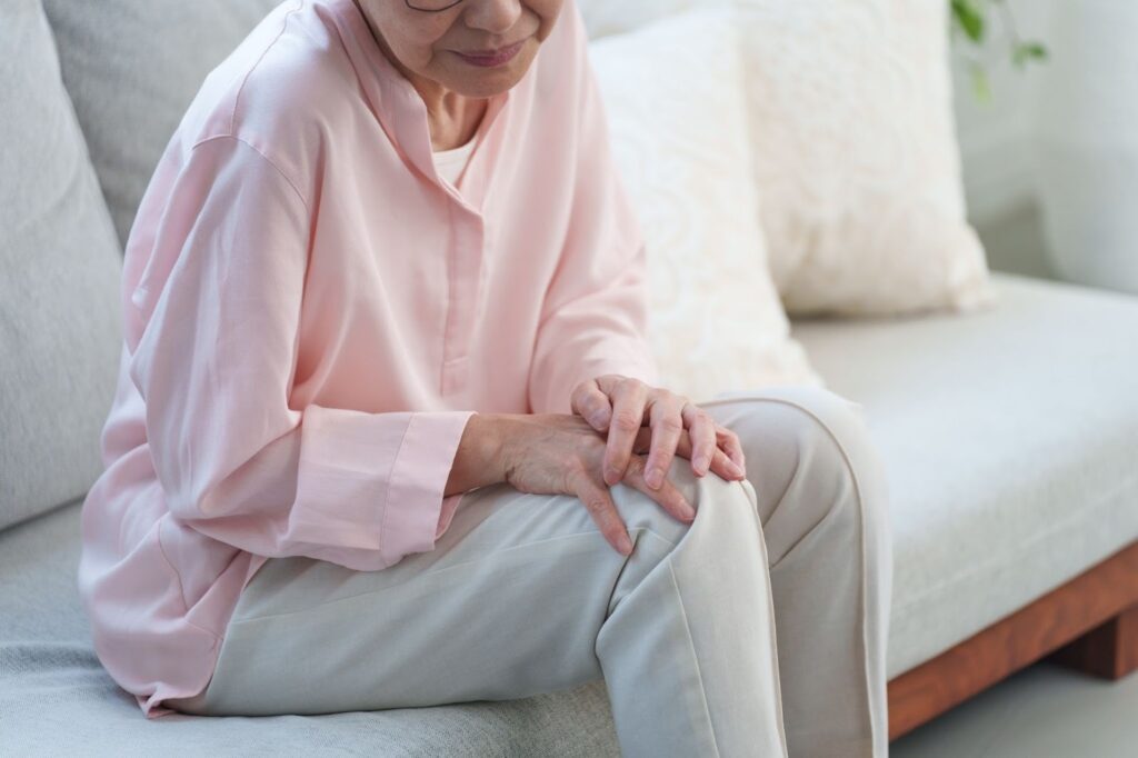筋肉の衰えによる膝痛で膝を押さえるシニア女性
