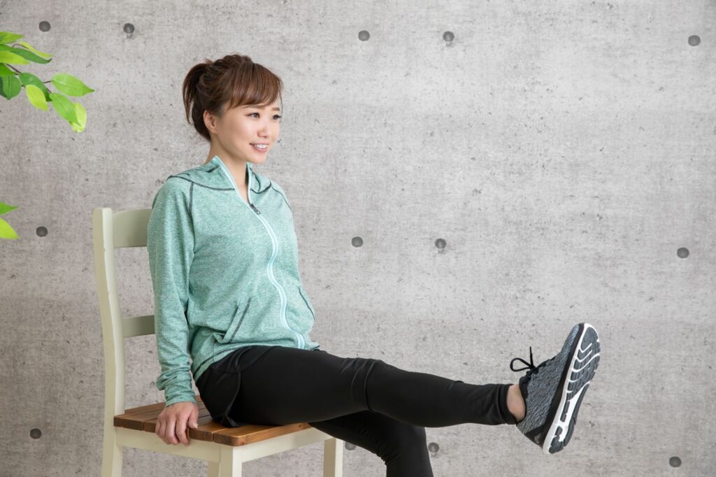 椅子に座って膝痛の筋肉トレーニング中の女性