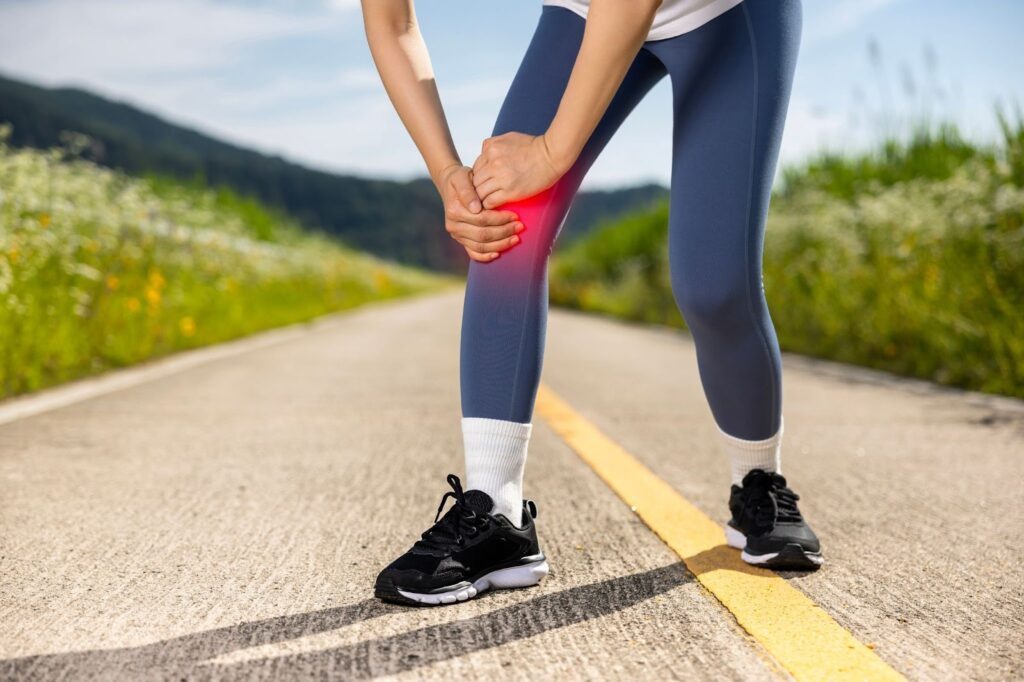 歩行中に膝の痛みを感じて膝を押さえる人の足元